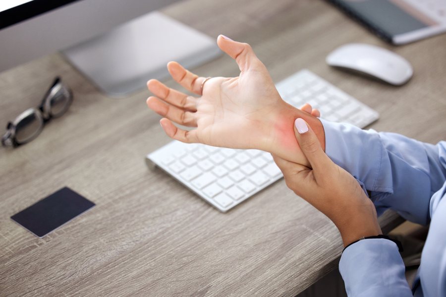 Office worker with carpal tunnel pain in her wrist, evaluated by Dr. Brian Donovan at Nuro Chiropractic in Brooklyn