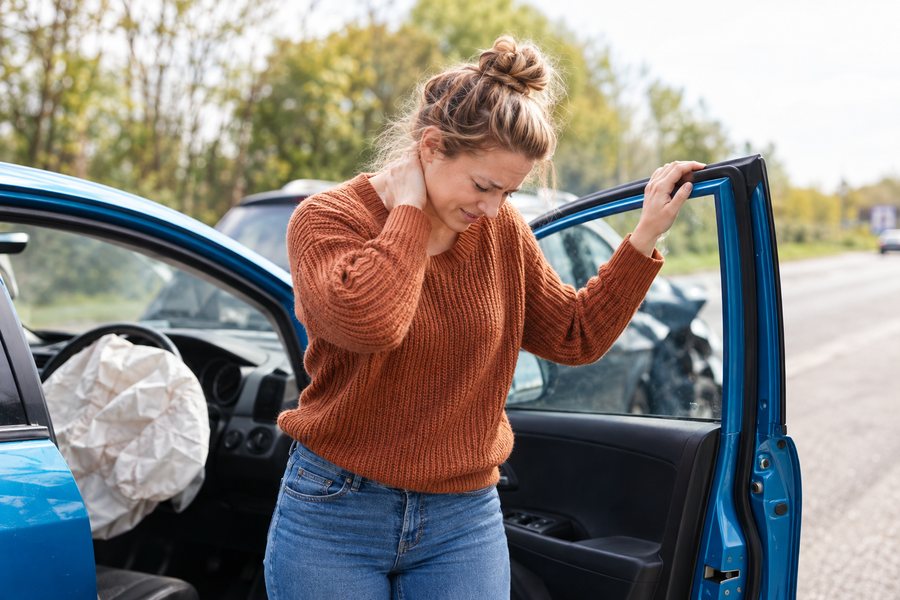 Woman with neck pain leaving her car after an accident in Brooklyn, treated at Nuro Chiropractic