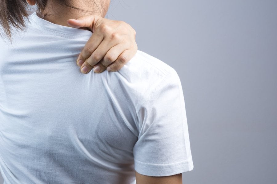 Woman holding her shoulder in pain, evaluated by Dr. Brian Donovan at Nuro Chiropractic in Brooklyn